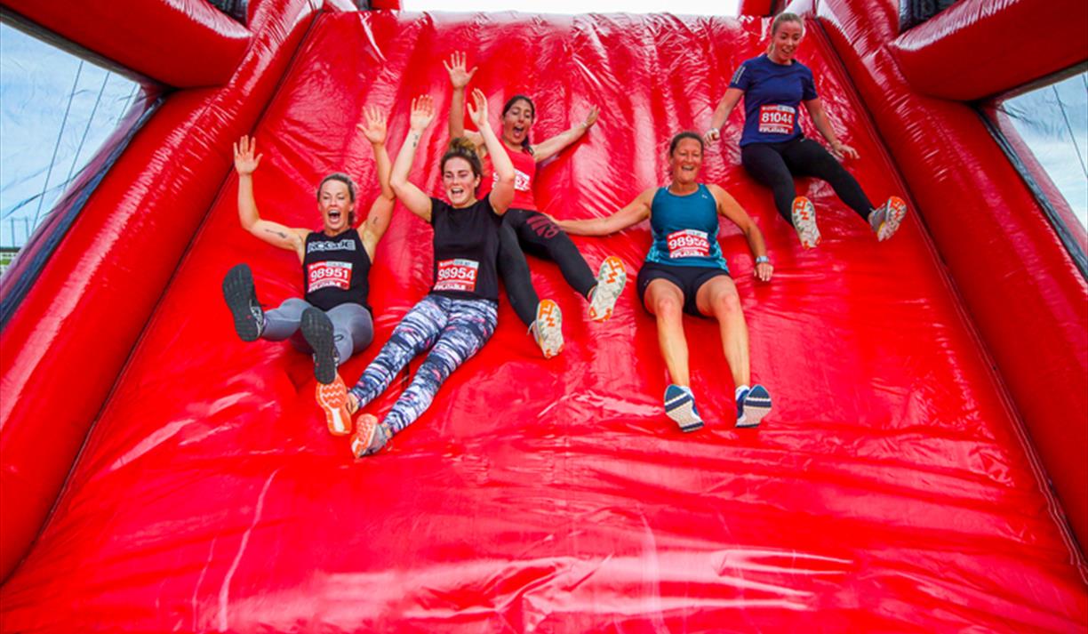 A group of people sliding down a bright red inflatable slide.
