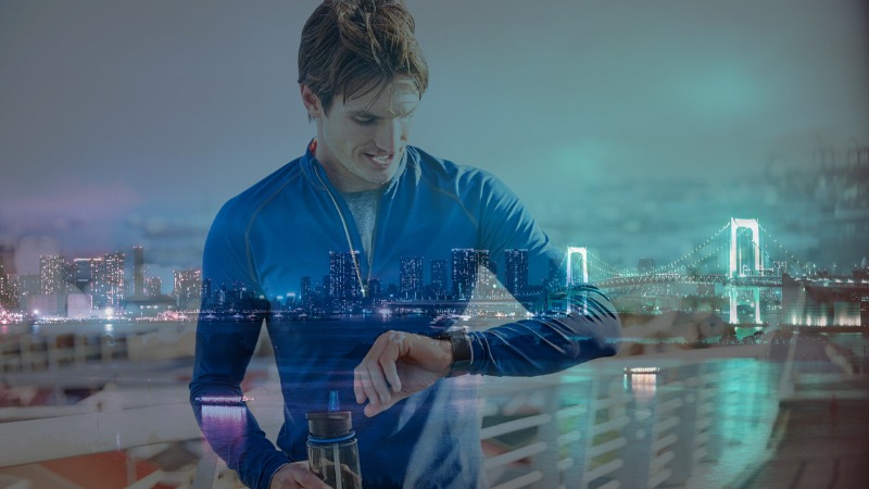 Overlayed image of a man in a running top looking at his watch against a New York skyline.