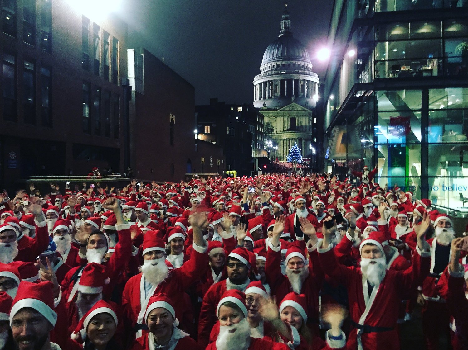 Large crowd of people running through London in Santa outfits.