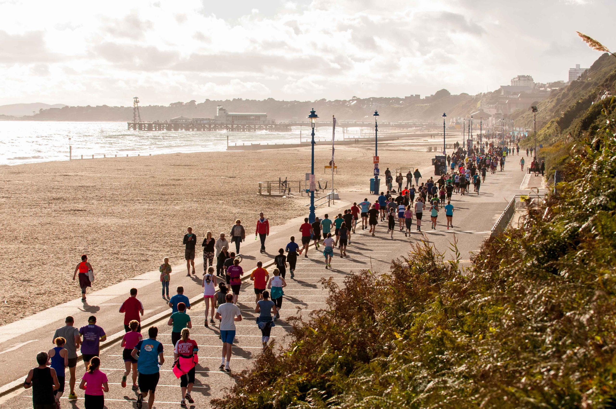 Group of people running alongside the beach in Bournemouth.