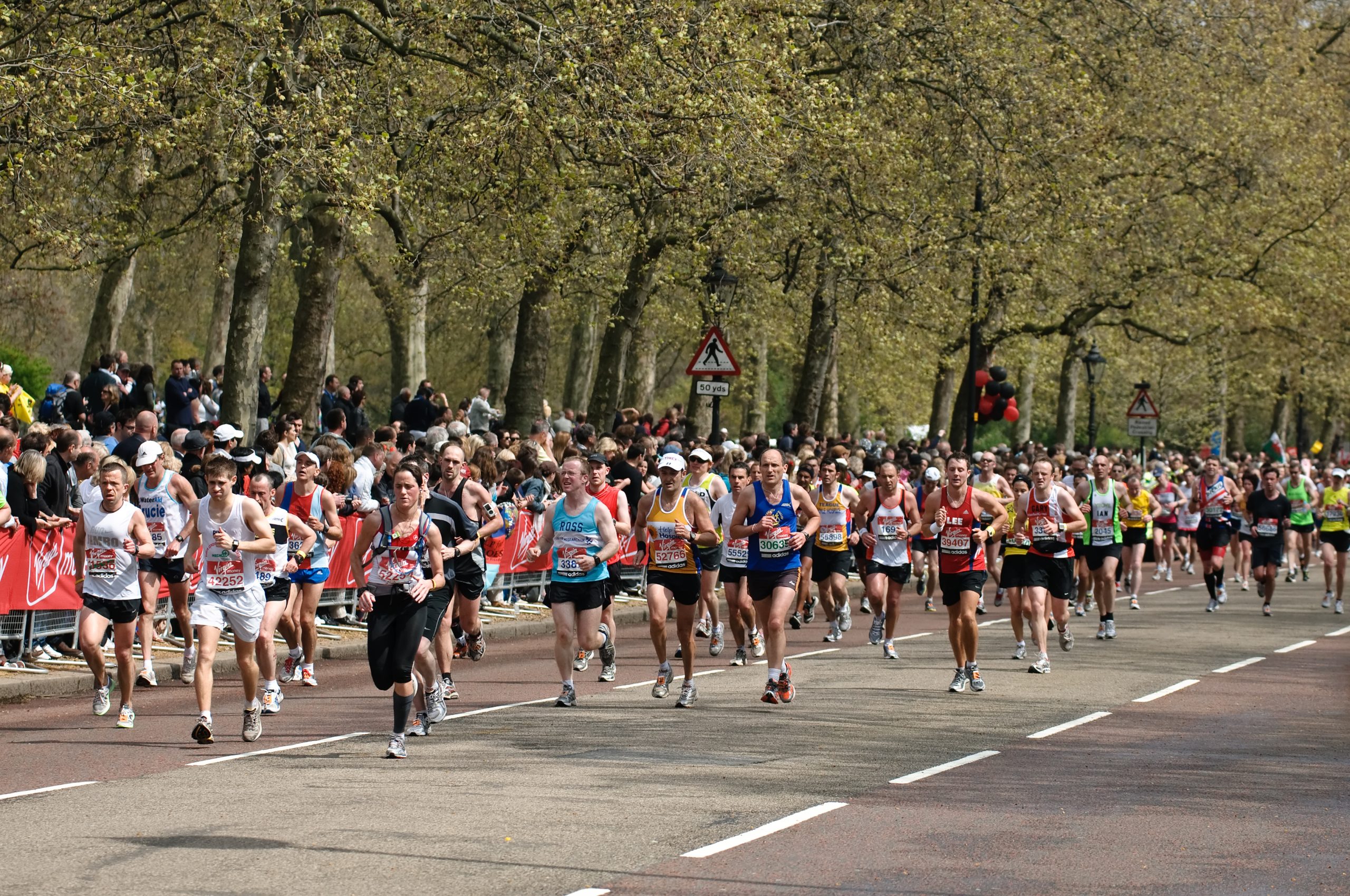 Lot of people running on a road with trees behind them.