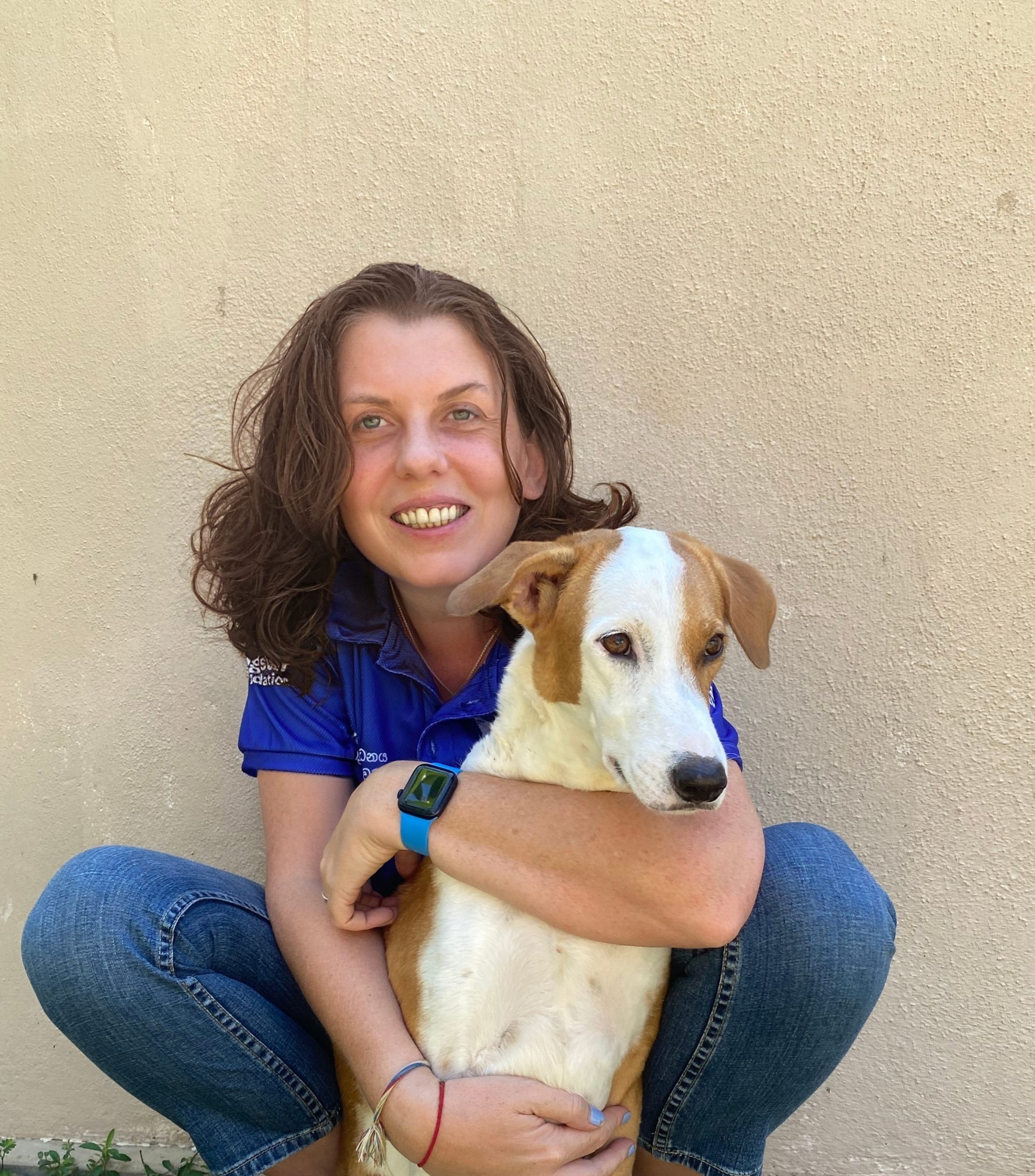 Sam crouching down hugging her rescue dog Star.